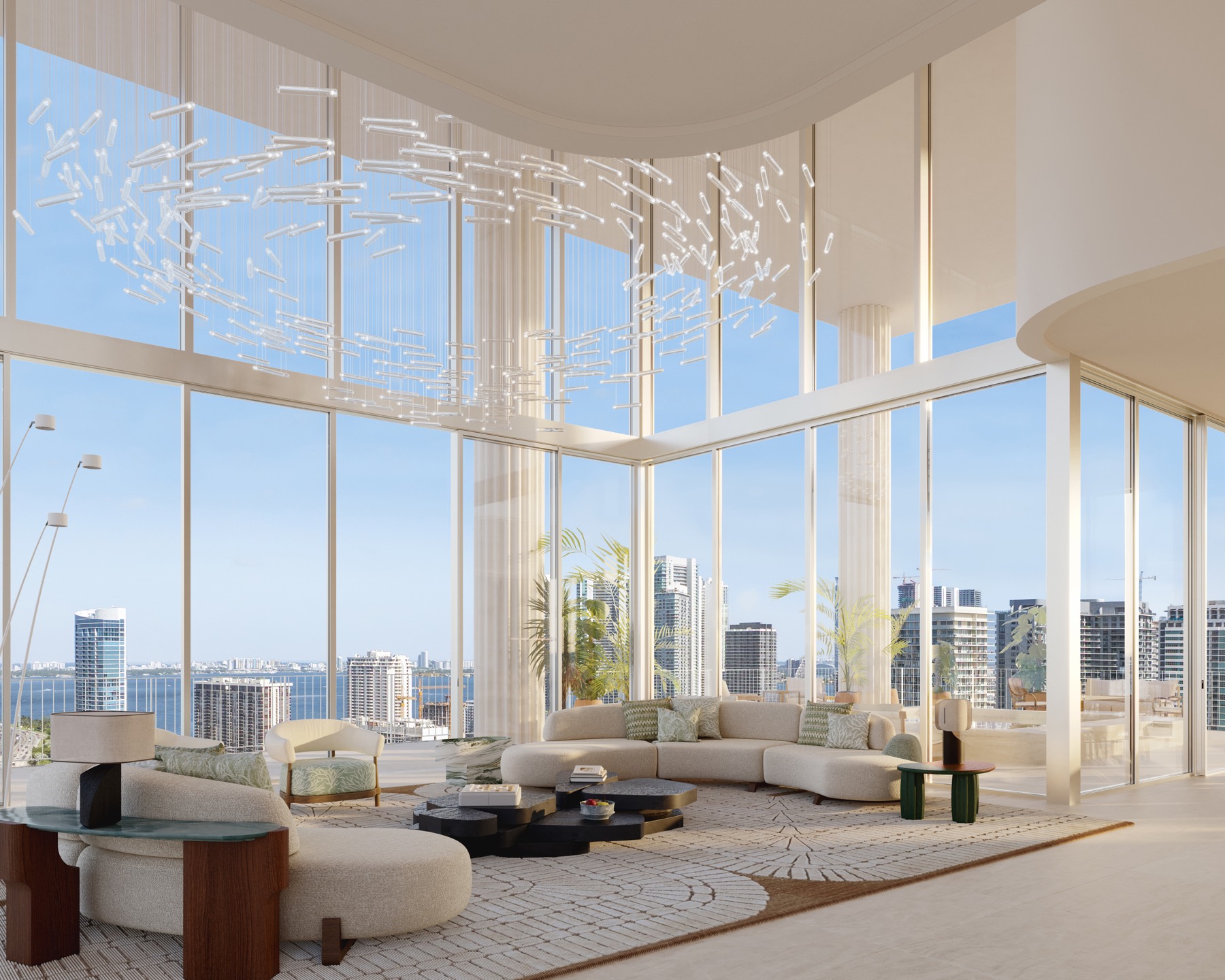 A penthouse living space at Fouquet's Hotel & Residences — 24-foot double-height volume, warm oak and stone, and a full wall of champagne-mullion glass opening to a wraparound terrace over Miami.