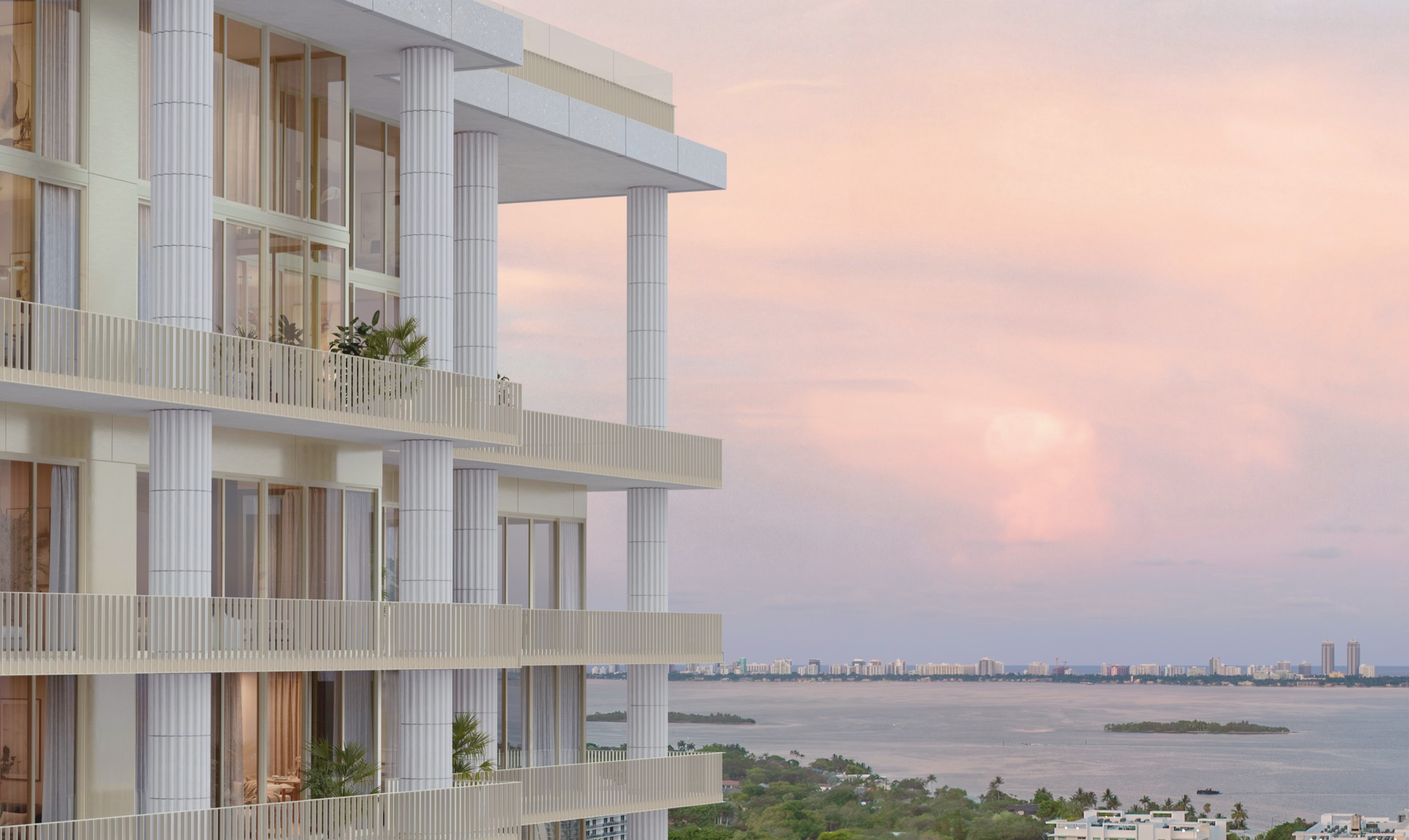 The upper terraces of Fouquet's Hotel & Residences at dusk — fluted columns, glass-railed balconies, and planted loggias overlooking Biscayne Bay and the islands beyond under a rosy Miami sky.